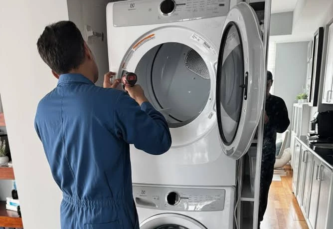 Technician servicing a stacked front-loading laundry dryer