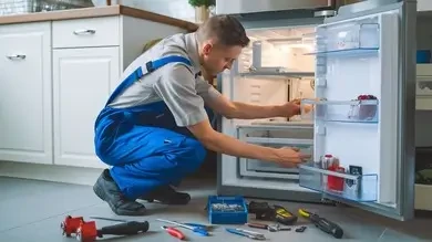 Technician checking a refrigerator with repair tools nearby
